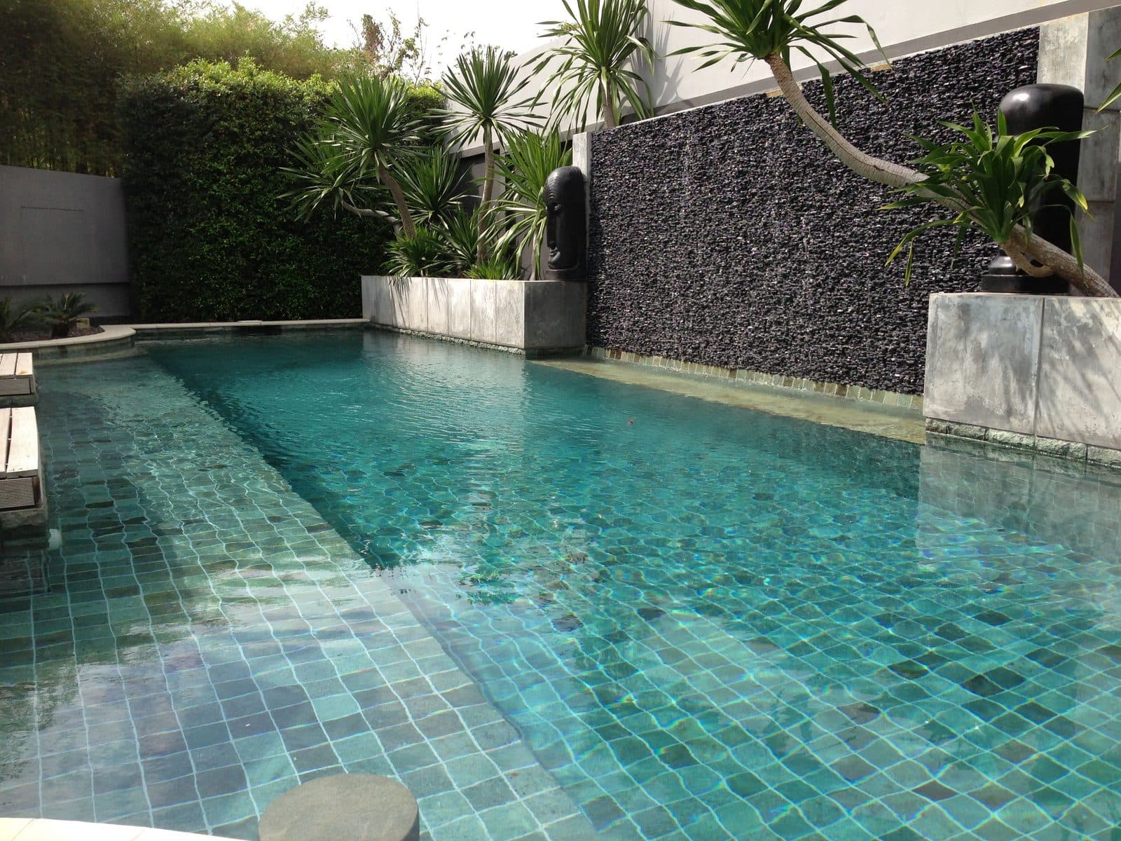Turquoise pool with a dark pebble waterfall wall